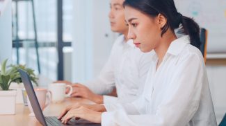 Asia young businesswoman watching tutorial about creative ideas at laptop computer in office.