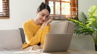 Happy Asian woman while using her laptop in the living room. work from home