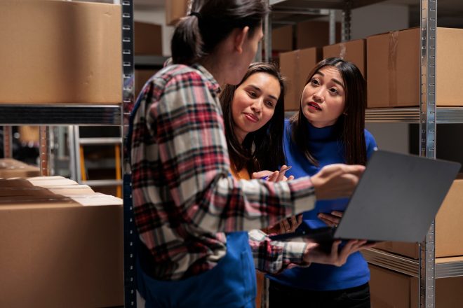 Warehouse asian manager explaining coworkers order tracking system